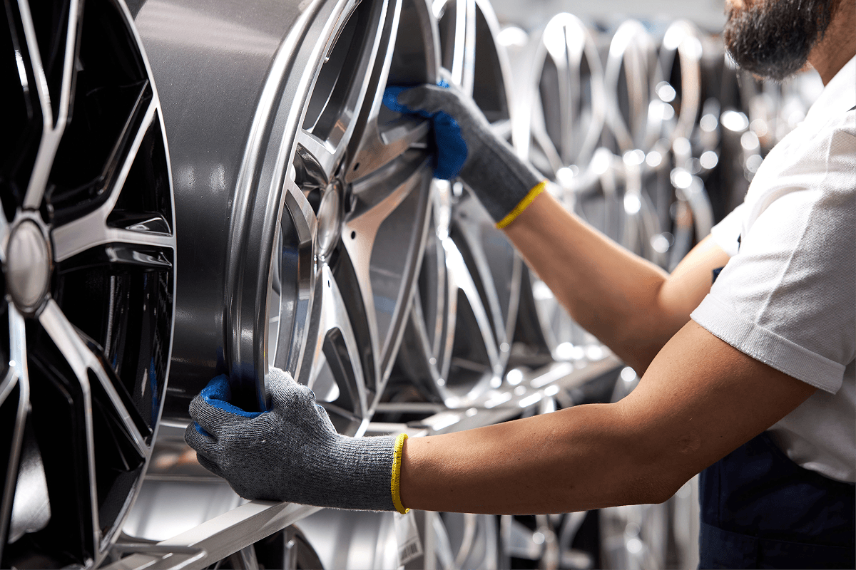 A man wearing gloves is working on a wheel.